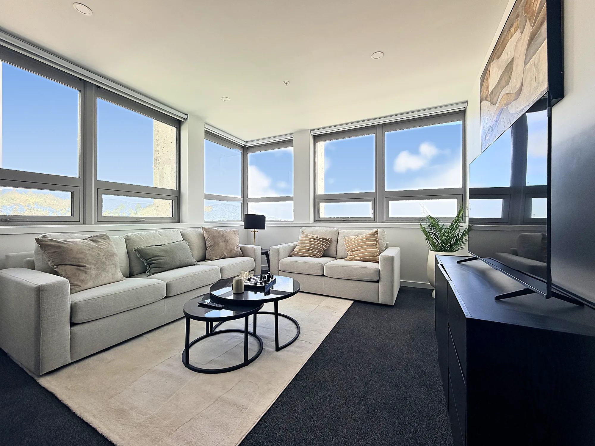 Corner living room with windows on two sides and valley views in a two bedroom corner display home at Avalon Apartments, Lower Hutt